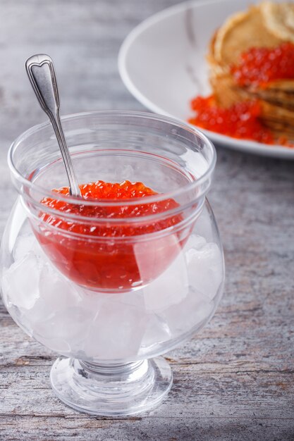 Red caviar in a glass glass with ice