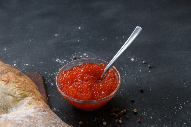 Red caviar in glass jar with silver spoon