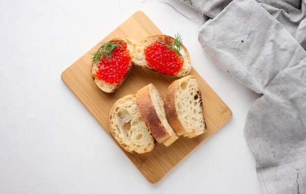 Red caviar on slices of white wheat bread on a white table concept of luxury and gourmet cuisine