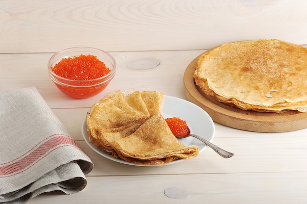 Caviale rosso nel cucchiaio e pancake nel piatto