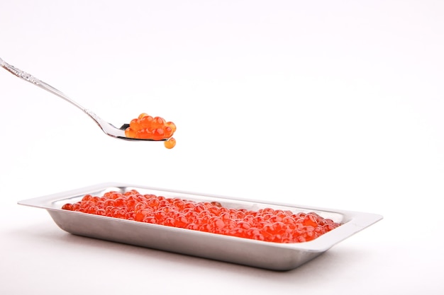 red caviar on a spoon on a white surface