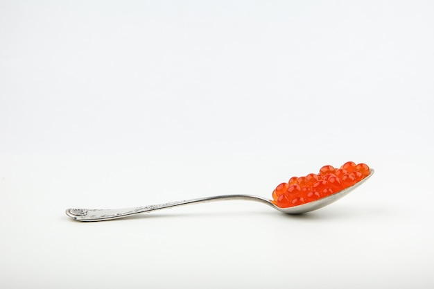 red caviar on a spoon on a white surface