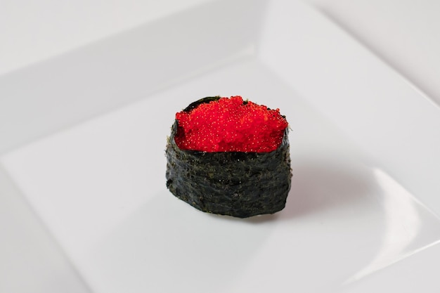 Red caviar sushi maki roll served on white plate