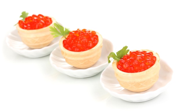 Red caviar in tartlets on little white saucers isolated on white