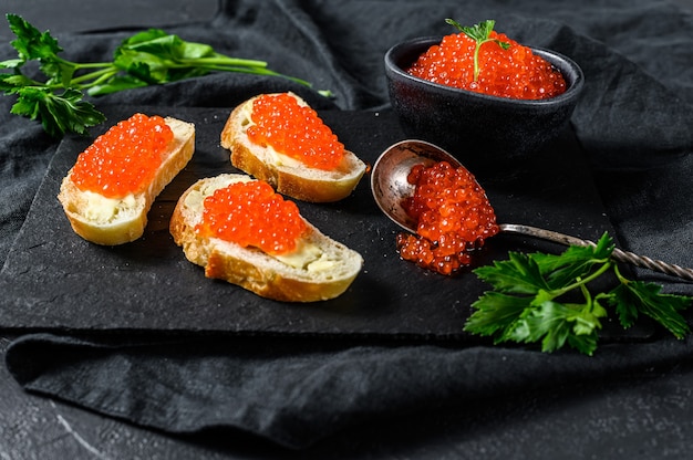 Red caviar in wooden bowl and bread