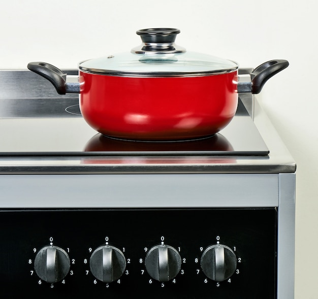 Red ceramic pan with cover on Electric hob