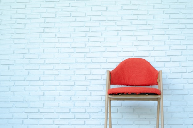 白いレンガの背景、モダンな部屋、コピースペースに赤い椅子。
