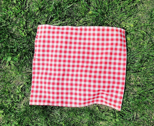 Photo red checkered cloth on green grass top view