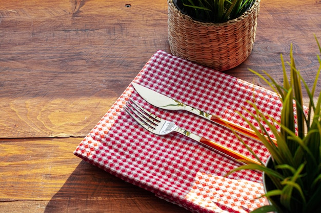 Red checkered napkin on wooden table with cutlery