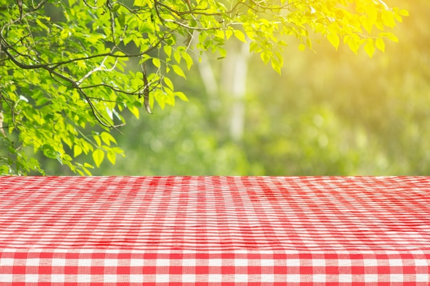 Red checkered tablecloth texture top view with abstract green bokeh background