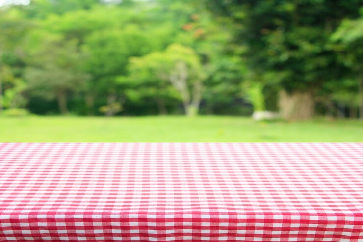 Photo red checkered tablecloth texture top view with abstract green bokeh from garden