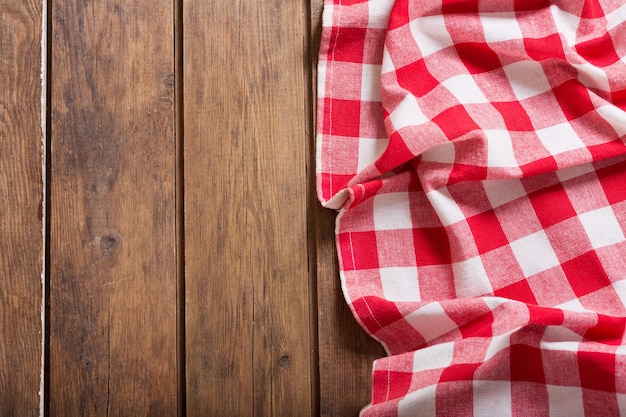 Red checkered tablecloth on wooden table, top view