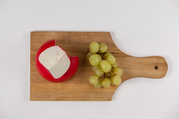 Red cheese and grapes on wooden board