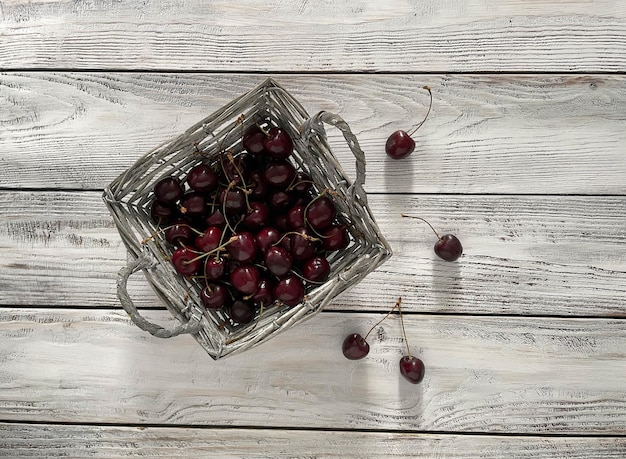 Photo red cherries in a basket on a wooden background top view