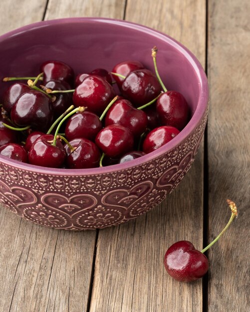 Red cherries on a bowl over wooden table.