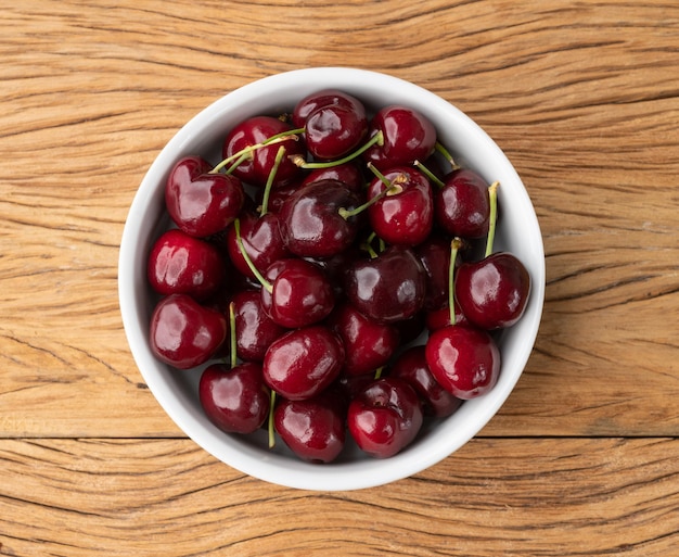 Red cherries on a bowl over wooden table