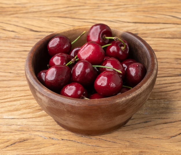 Red cherries on a bowl over wooden table