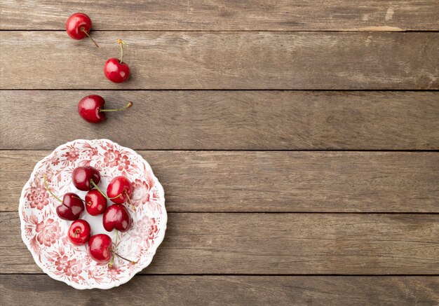 Foto ciliege rosse su un piatto su un tavolo in legno con spazio di copia.