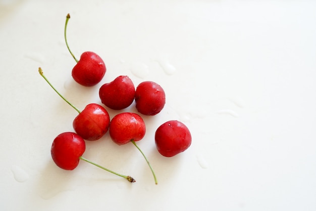 Red cherries on white table with copy space. 