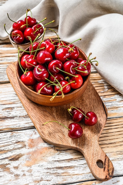Red cherries in a wooden bowl. White background. Top view.