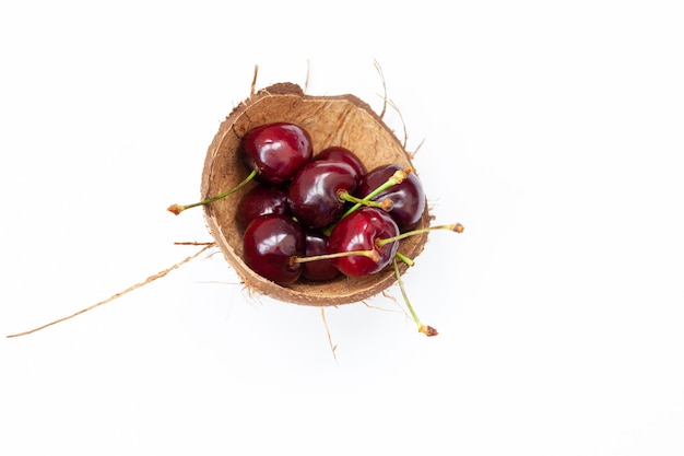 Ciliegia rossa nel guscio di noce di cocco, isolata.