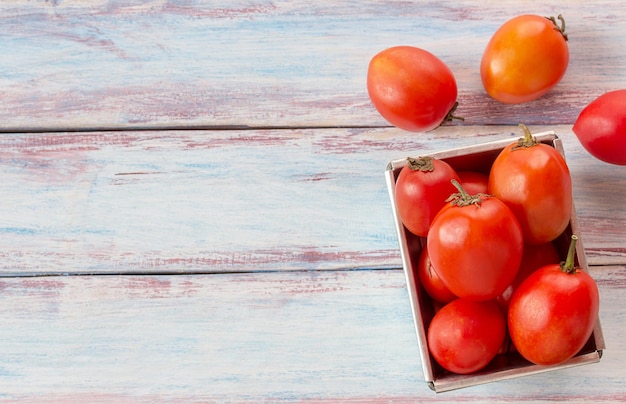 Red cherry plum tomatoes on wood table background