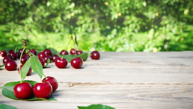 Photo red cherry on a wooden table against the backdrop of an orchard