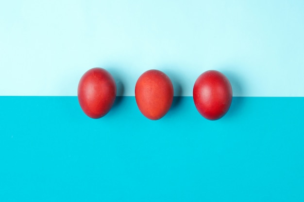 Red chicken eggs on color paper table. Minimalistic Easter concept