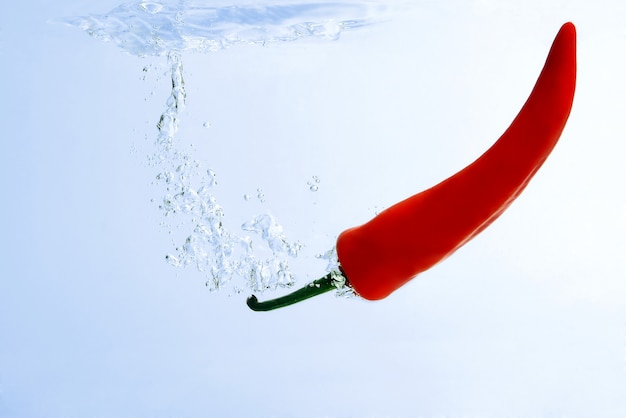 Red chili pepper falling in water