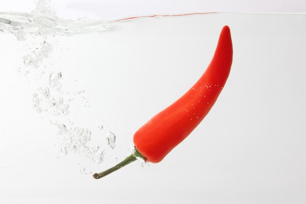 Red chili pepper falling in water