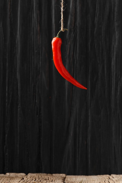 Red chili pepper hanging against a dark wooden background Closeup