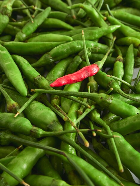 A Red Chili pepper with Green chili peppers