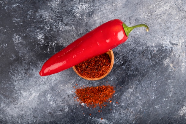 Red chili pepper with ground pepper flakes on marble.