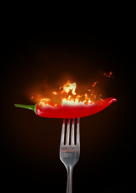 Red chili peppers on fork in flame Hot red chili peppers on a fork in flame on a black background