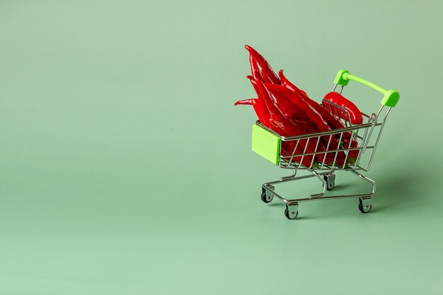 Красный перец чили в продуктовой тележке, концепция покупок в супермаркете.