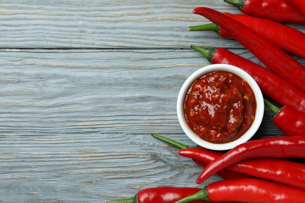 Red chili peppers and sauce on gray wooden