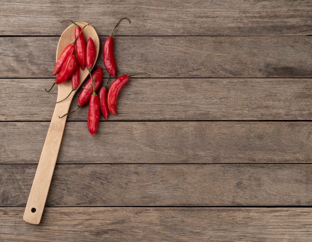 Red chili peppers on a spoon over wooden table with copy space.