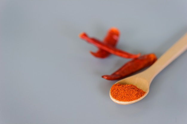 Red chili powder or paprika in a wooden bowl on a dark background, close-up. Cooking ingredients, flavor.