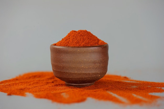 Red chili powder or paprika in a wooden bowl on a dark background, close-up. Cooking ingredients, flavor.