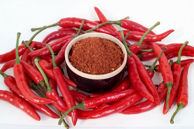 Red chilli and chilli powder on white scene.                               