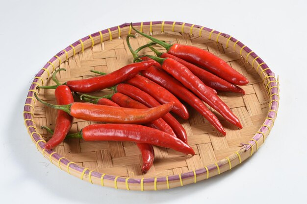 Red chilli pepper in bamboo plate on white background