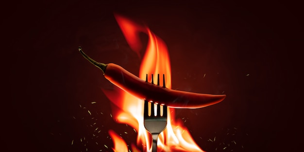Red chilli peppers with a fork on a fire element and hot\
background