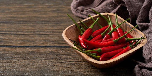 red chillies in the wooden bowl on a wood background