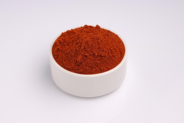 Красный холодный порошок индийских специй в белой миске с белой текстурой или фоном