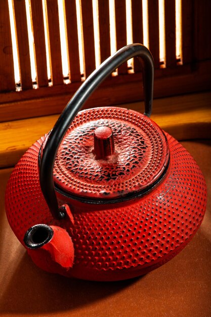 Red Chinese teapot on a background of a wooden window with sunbeams. tea ceremony