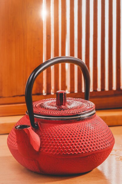 Red Chinese teapot on a background of a wooden window with sunbeams. tea ceremony