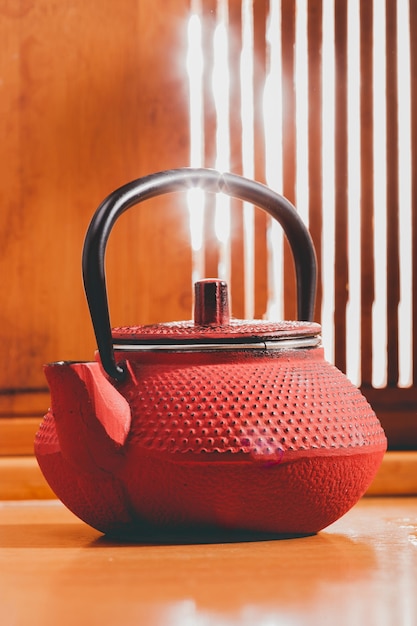 Red Chinese teapot on a background of a wooden window with sunbeams. tea ceremony