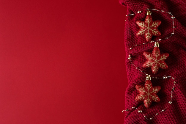 Red Christmas background with red Christmas toys and beads on a red knitted fabric.