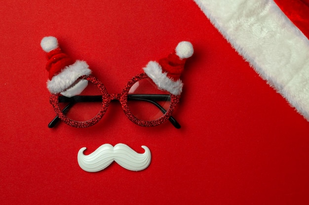 Red Christmas background with Santa glasses and white hipster mustache Christmas symbols