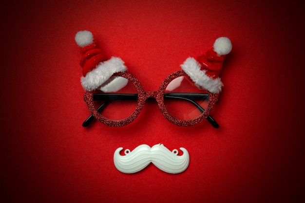 Red Christmas background with Santa glasses and white hipster mustache. 